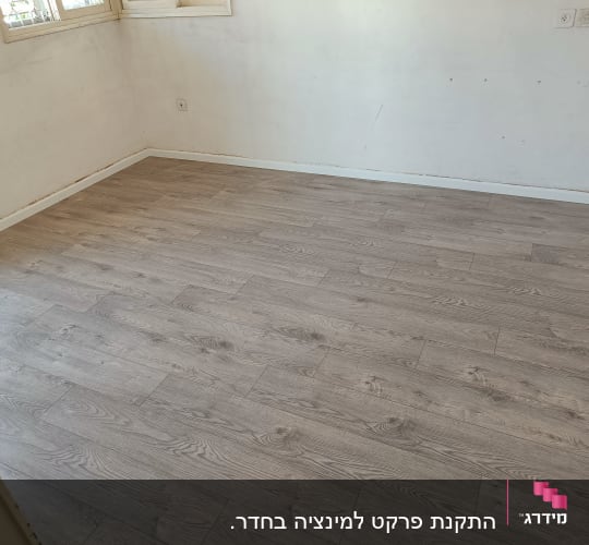 רצפת פרקט עץ בהירה בחדר ריק עם קירות לבנים